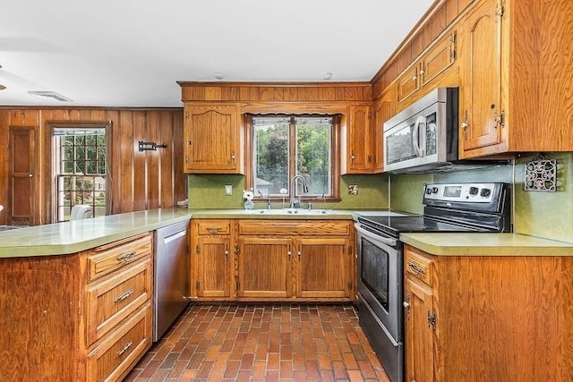 57 Rudon Dr, North Attleboro, MA 02760 - kitchen featuring appliances with stainless steel finishes, a peninsula, light countertops, brown cabinetry, and wooden walls