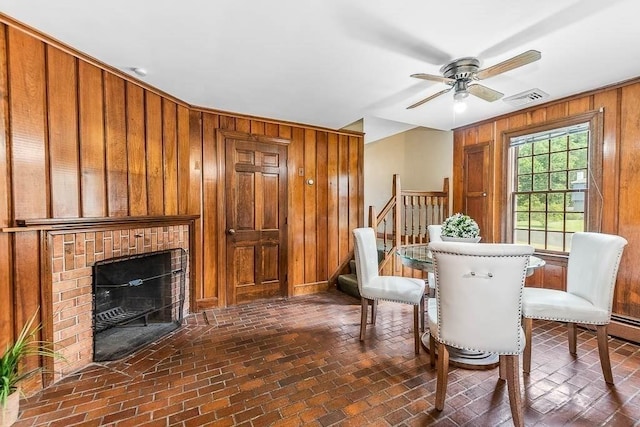 57 Rudon Dr, North Attleboro, MA 02760 - dining room featuring wood walls, brick floors, ceiling fan, a fireplace, and stairway