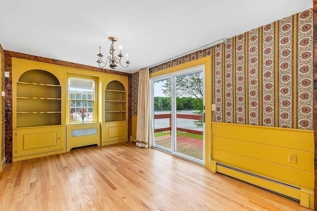 57 Rudon Dr, North Attleboro, MA 02760 - unfurnished dining area featuring a baseboard radiator, a chandelier, built in shelves, wood finished floors, and wallpapered walls