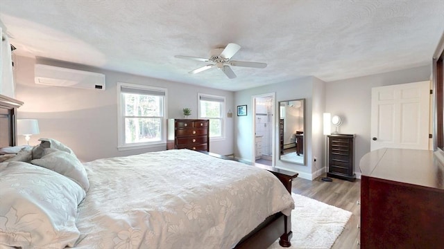 1000 Forest St, North Andover, MA 01845 - bedroom with an AC wall unit, light wood finished floors, baseboards, ceiling fan, and a textured ceiling