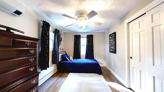 1000 Forest St, North Andover, MA 01845 - bedroom with baseboard heating, a wall mounted air conditioner, wood finished floors, baseboards, and a ceiling fan
