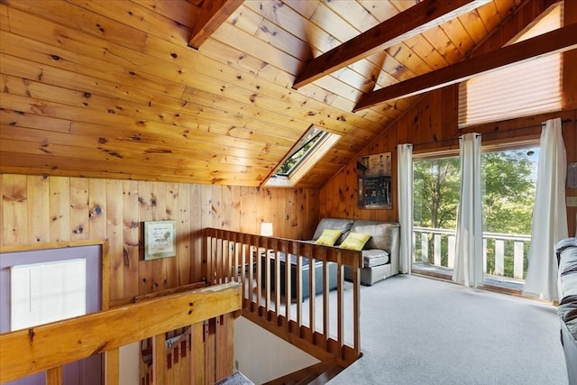 additional living space with wood ceiling, vaulted ceiling with skylight, wooden walls, and carpet floors