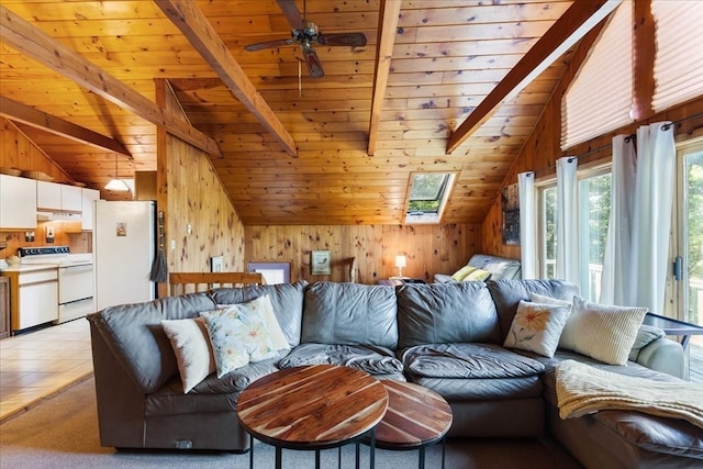 carpeted living room with wood ceiling, vaulted ceiling with skylight, wood walls, and ceiling fan