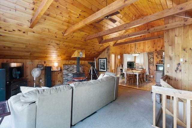 living room featuring wood ceiling, a wood stove, ceiling fan, and wooden walls