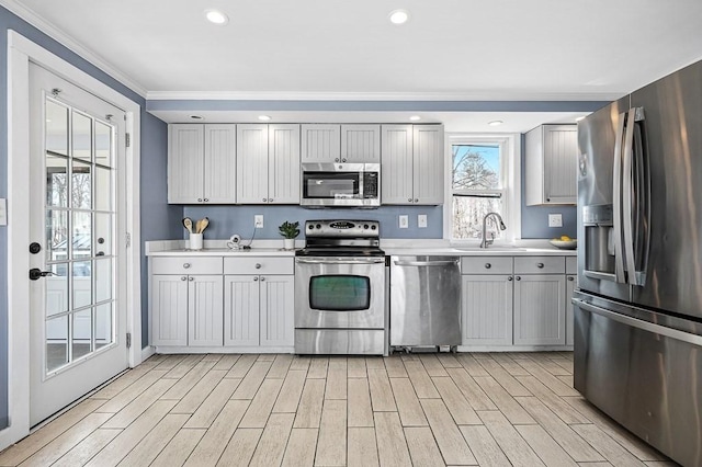 kitchen featuring gray cabinetry, wood finish floors, light countertops, stainless steel appliances, and a sink