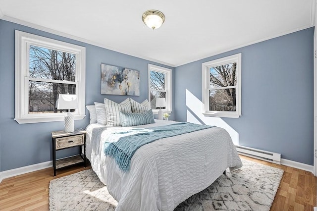 bedroom featuring wood finished floors, baseboards, and a baseboard radiator