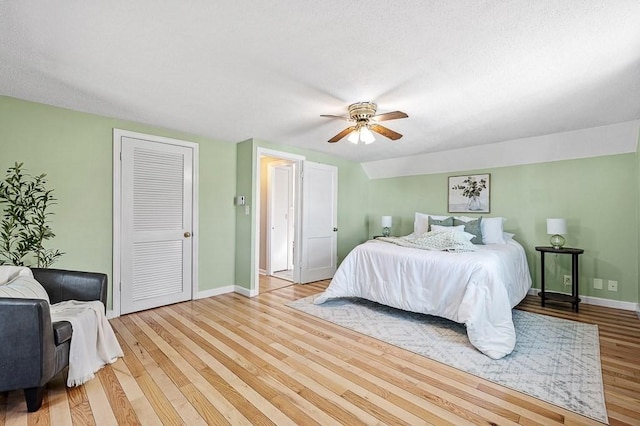 bedroom featuring light wood-type flooring, baseboards, a closet, and a ceiling fan