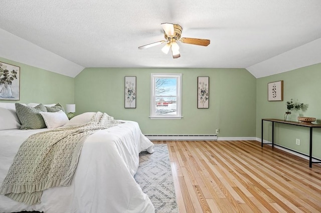 bedroom featuring wood finished floors, baseboards, vaulted ceiling, a textured ceiling, and a baseboard heating unit