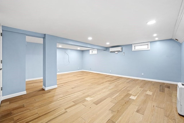 basement with recessed lighting, baseboards, an AC wall unit, and light wood-style flooring