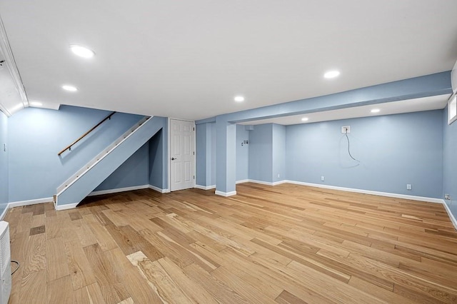 finished below grade area featuring recessed lighting, baseboards, stairs, and light wood-style floors