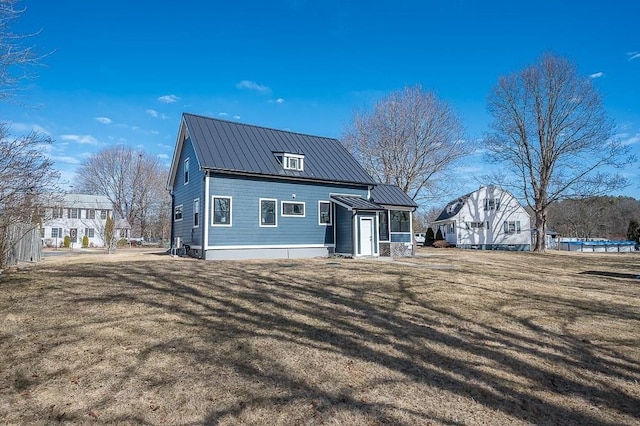 back of house with a standing seam roof, a yard, and metal roof