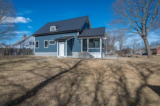 back of house featuring metal roof, fence, a lawn, and a standing seam roof