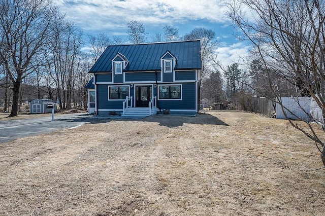 view of front of house with a standing seam roof, a storage shed, an outbuilding, and metal roof