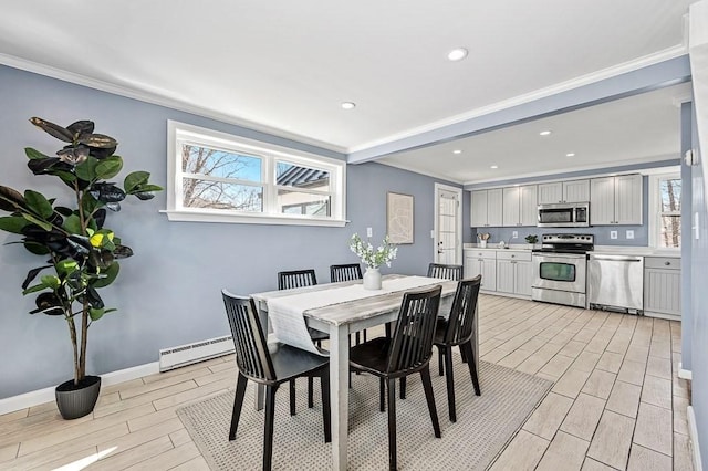 dining room with crown molding, a baseboard heating unit, baseboards, and wood tiled floor