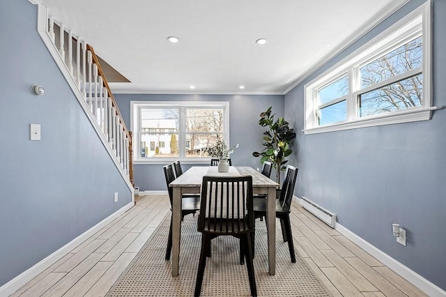 dining room featuring a wealth of natural light, baseboard heating, and wood tiled floor