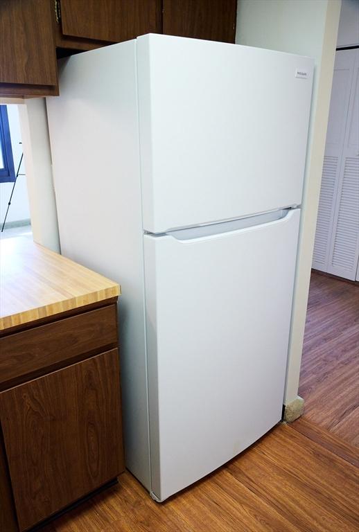 kitchen featuring white refrigerator, dark brown cabinets, and light wood-type flooring