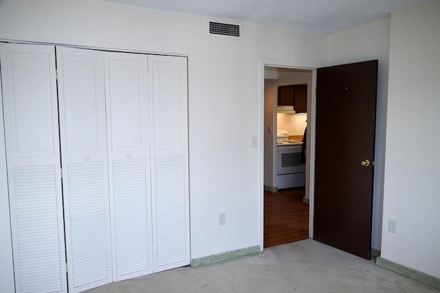 unfurnished bedroom with light colored carpet and a closet