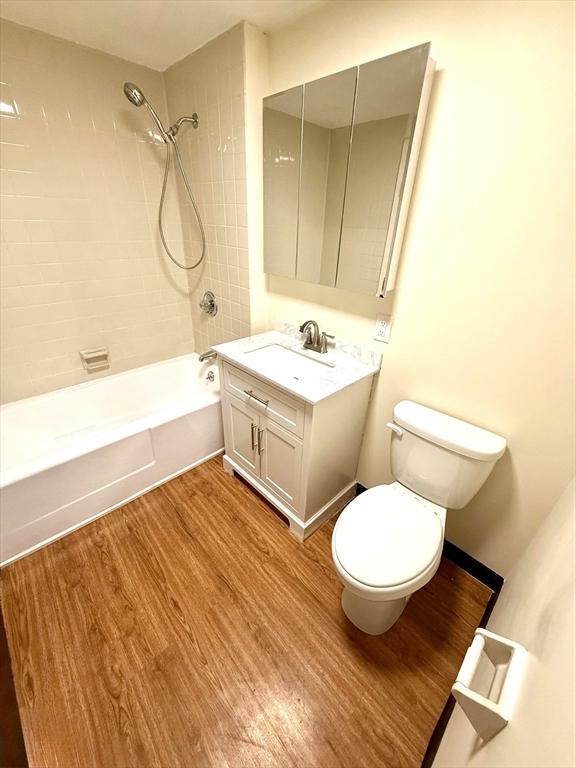 full bathroom featuring vanity, hardwood / wood-style flooring, toilet, and tiled shower / bath