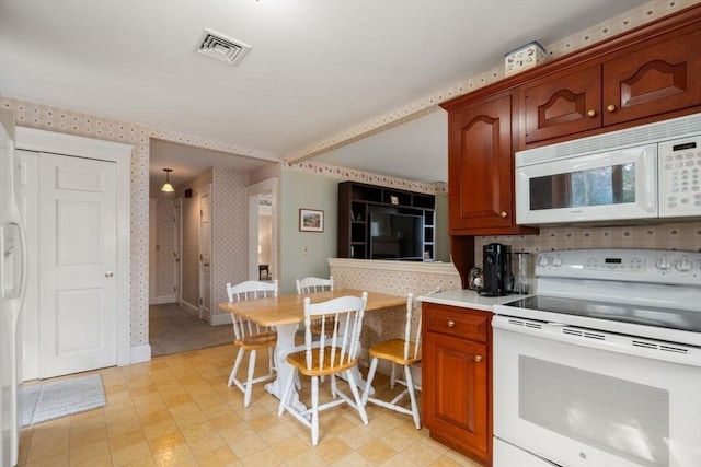 kitchen featuring light countertops, light floors, visible vents, white appliances, and wallpapered walls