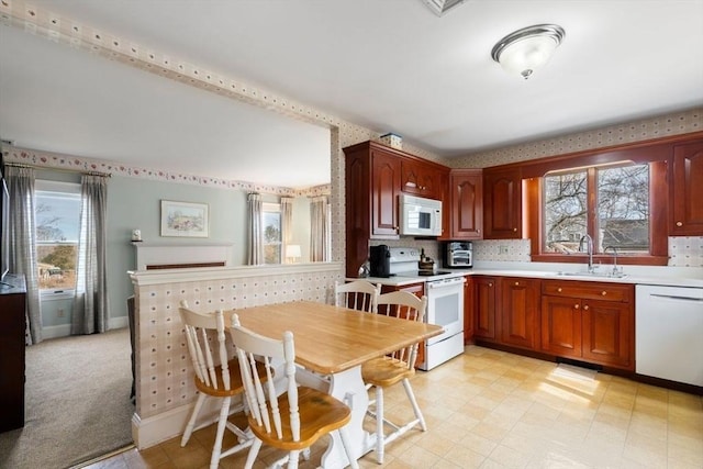 kitchen with plenty of natural light, white appliances, light countertops, and a sink