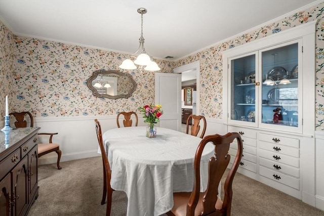 dining area with light colored carpet, wallpapered walls, a notable chandelier, and wainscoting