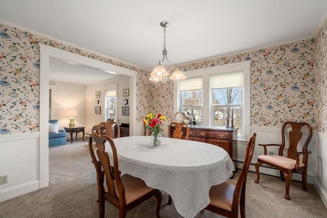 carpeted dining area featuring ornamental molding, wallpapered walls, and wainscoting