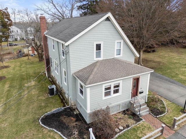 exterior space featuring a front yard, central AC, a shingled roof, and a chimney