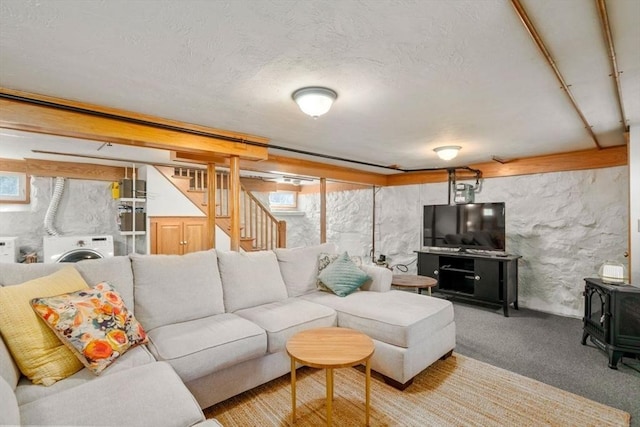 carpeted living area with stairs, washer / clothes dryer, a wood stove, and a textured ceiling