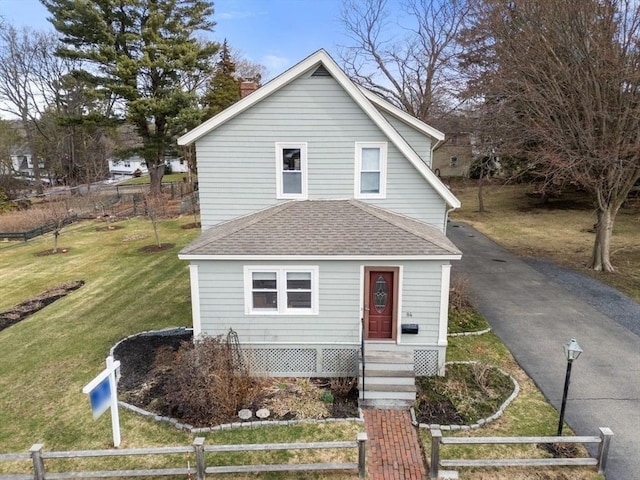 view of front of property featuring a chimney, fence, a front lawn, and roof with shingles