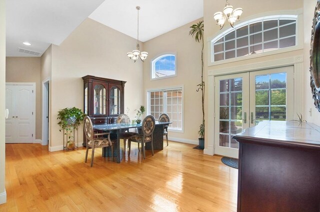 dining space featuring a notable chandelier, a wealth of natural light, light hardwood / wood-style floors, and french doors