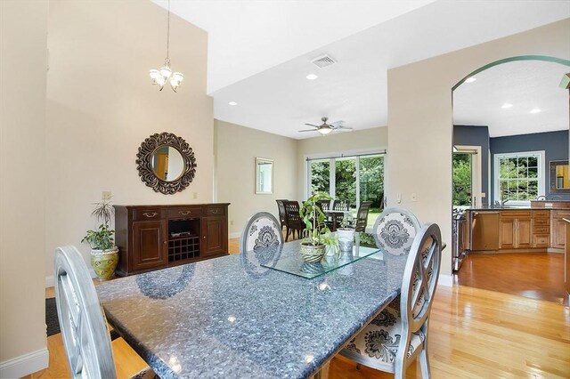 dining room with light hardwood / wood-style flooring and ceiling fan with notable chandelier