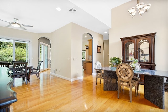 dining space with ceiling fan with notable chandelier and light hardwood / wood-style floors