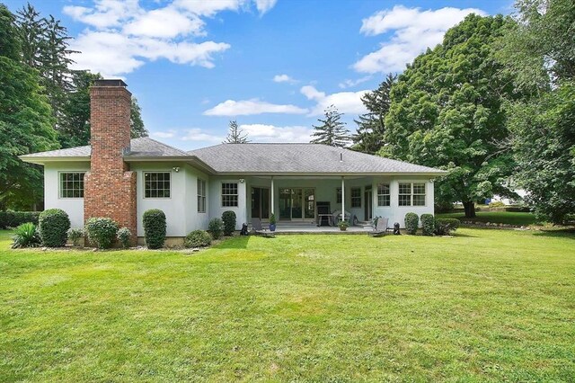 rear view of property featuring a yard and a patio area