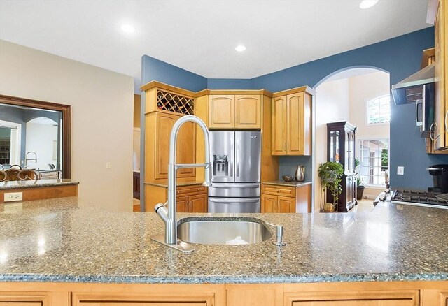 kitchen with stainless steel refrigerator with ice dispenser, sink, and dark stone counters