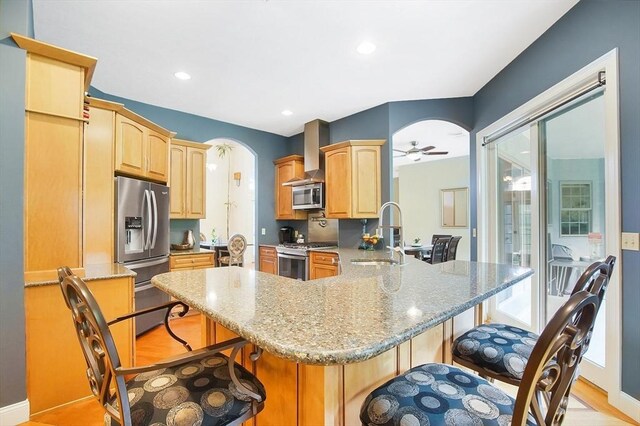 kitchen with a kitchen breakfast bar, stainless steel appliances, light hardwood / wood-style floors, and kitchen peninsula