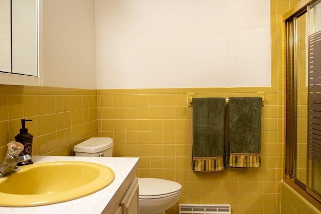 full bathroom with tile walls, vanity, combined bath / shower with glass door, and toilet