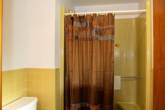 bathroom with tile walls, a shower with curtain, and toilet