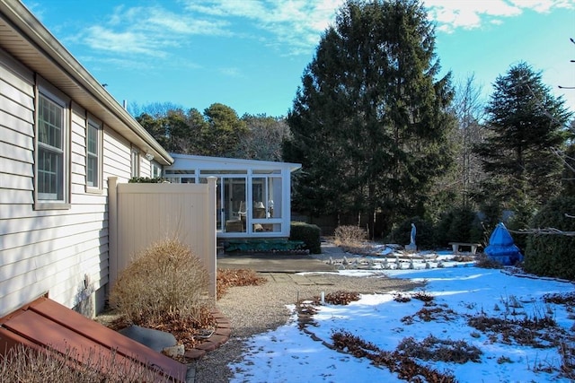 yard covered in snow featuring a sunroom