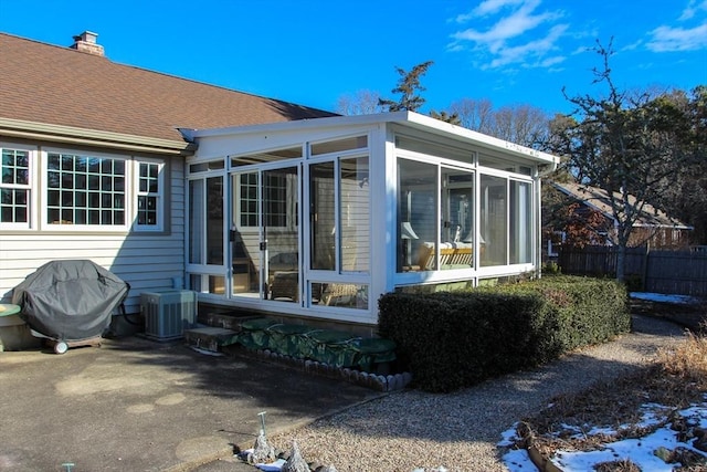 back of property with central AC and a sunroom