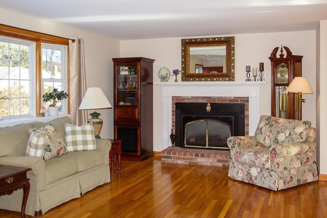 living area featuring a brick fireplace and hardwood / wood-style flooring