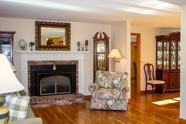 living area featuring a brick fireplace and hardwood / wood-style flooring