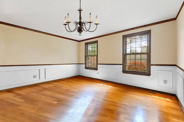 empty room featuring an inviting chandelier, ornamental molding, and wood-type flooring