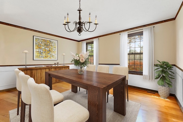 dining room featuring crown molding, a notable chandelier, light hardwood / wood-style floors, and plenty of natural light