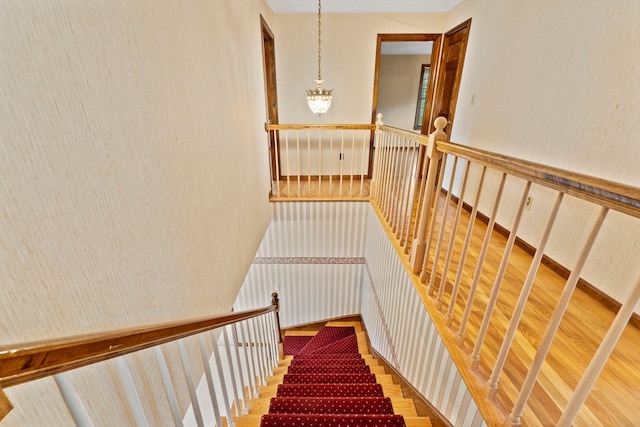 staircase with wood-type flooring and a chandelier