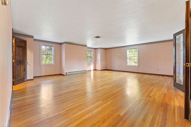 spare room with a baseboard radiator, light hardwood / wood-style flooring, a textured ceiling, and plenty of natural light