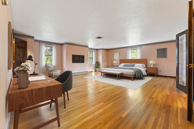 bedroom featuring ornamental molding, light hardwood / wood-style flooring, a textured ceiling, and baseboard heating