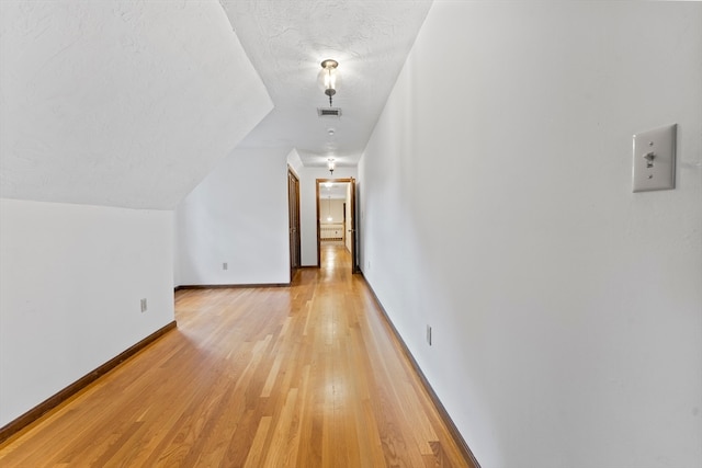 bonus room with a textured ceiling, lofted ceiling, and light hardwood / wood-style flooring