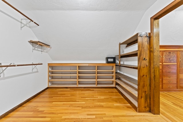 walk in closet featuring light hardwood / wood-style floors and vaulted ceiling