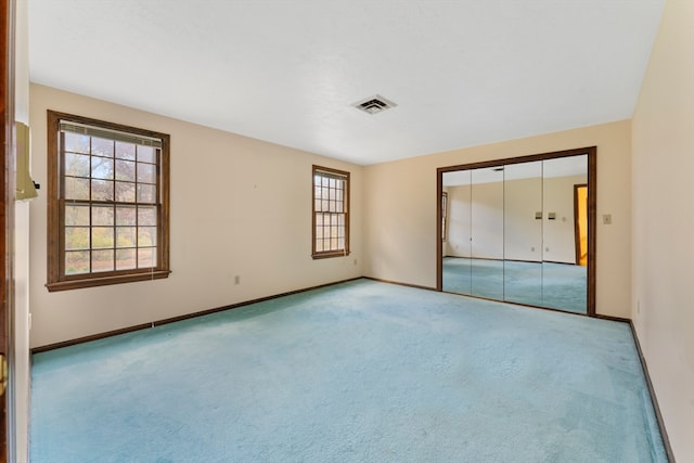 unfurnished bedroom with light carpet, multiple windows, and a closet