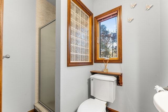 bathroom featuring toilet and a shower with shower door